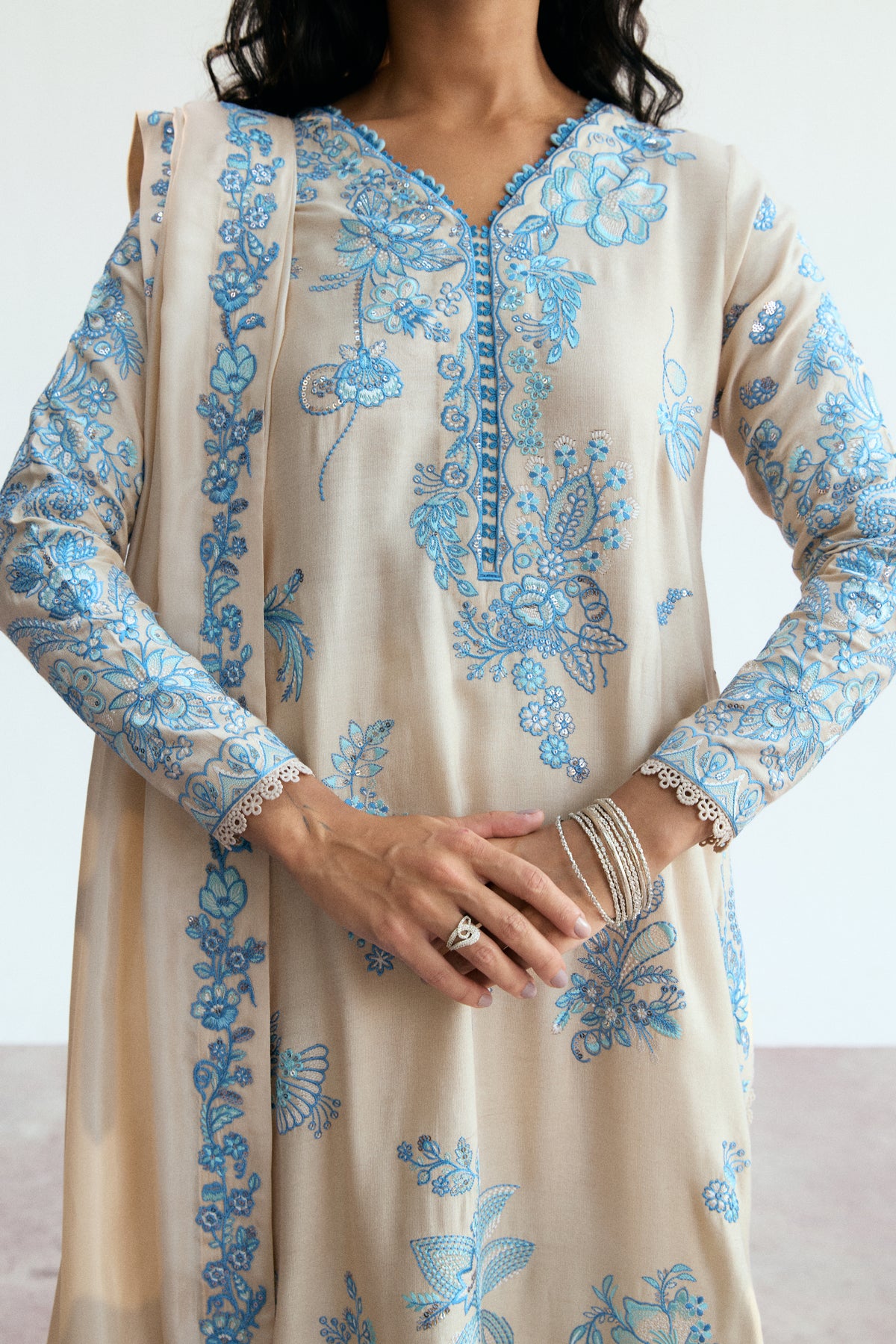 Scalloped lace trims and blue floral embroidery on the sleeves of the Opalite Set cream shirt.