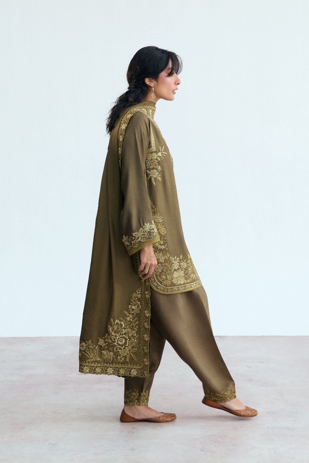 Rounded hem with piping finish and embroidered neckline detail on a luxury green Pakistani kameez, wedding function wear