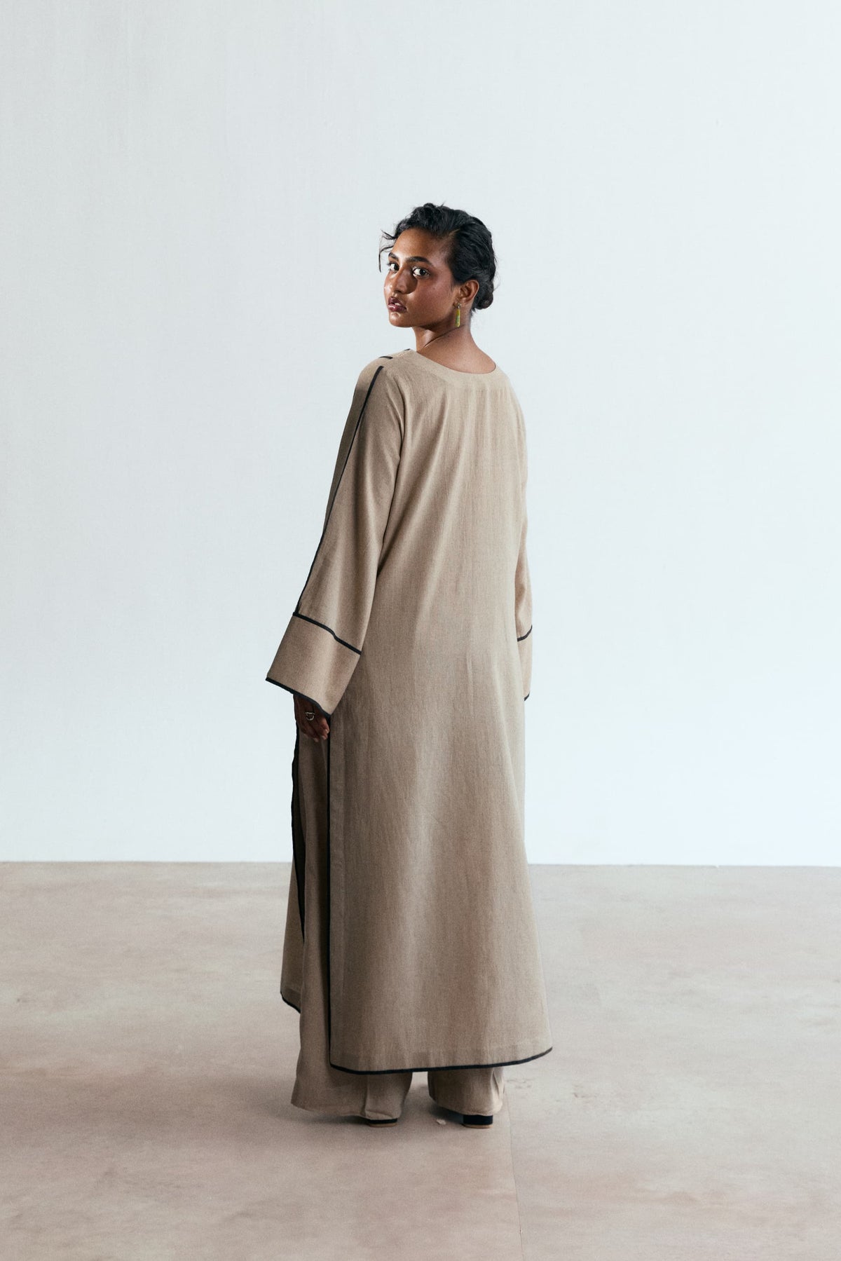 Stone Set — back view of sand beige linen-cotton Pakistani kameez with black piping and wide-leg trousers UK