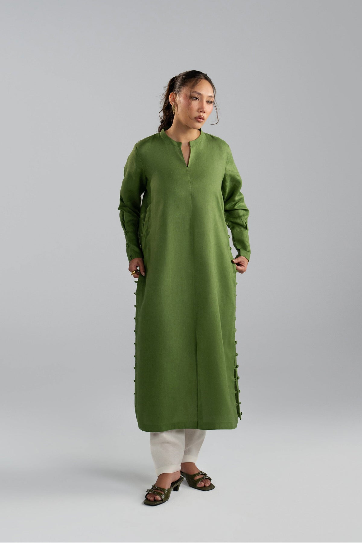Woman wearing a green long-sleeve dress with white pants