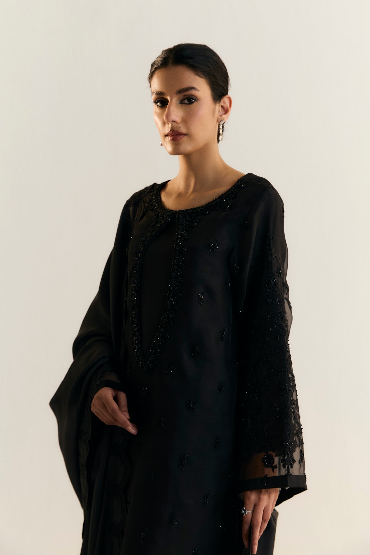 Elegant all-black Pakistani designer organza suit with keyhole neckline and hand-embroidered petal-edge dupatta by Mannam