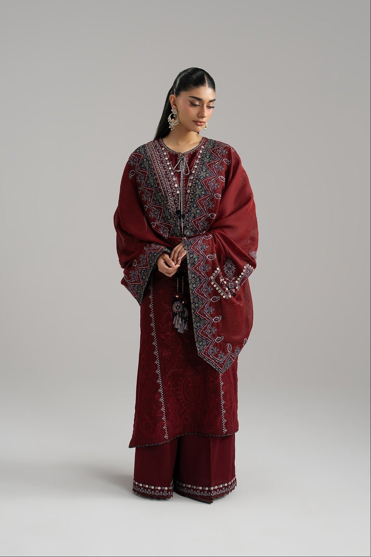 Deep maroon Pakistani kameez detail — tassels and ajrak accents at neckline | Mannam Saffron Set