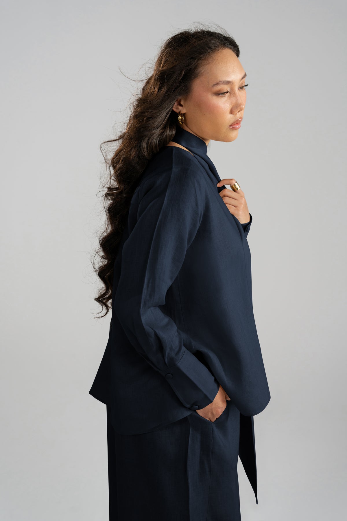 Side-back profile view of the Cove Set in navy blue pure linen, showcasing the elegant drape of the matching short scarf and wide-leg trousers from the linen collection.