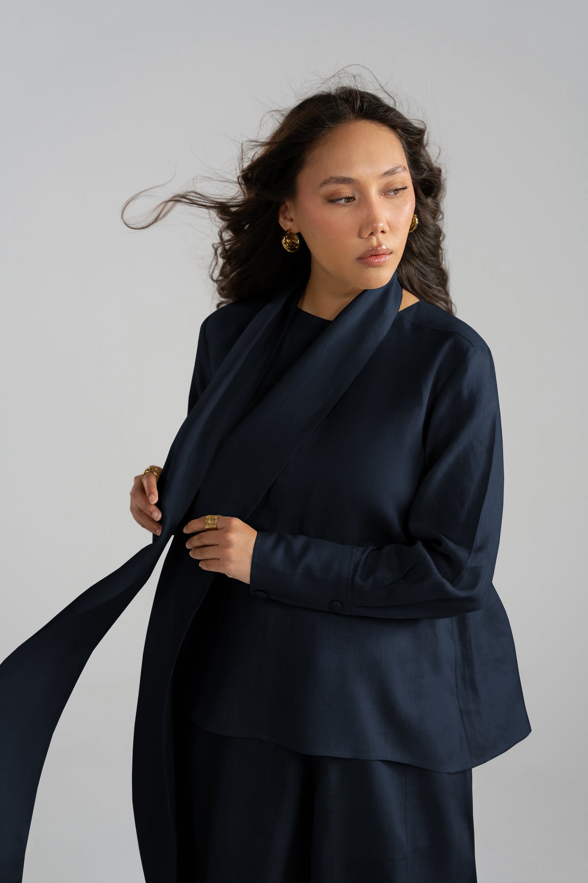 Action shot of the Cove Set in navy blue, showcasing the movement of the pure linen short scarf and short shirt from the linen collection.