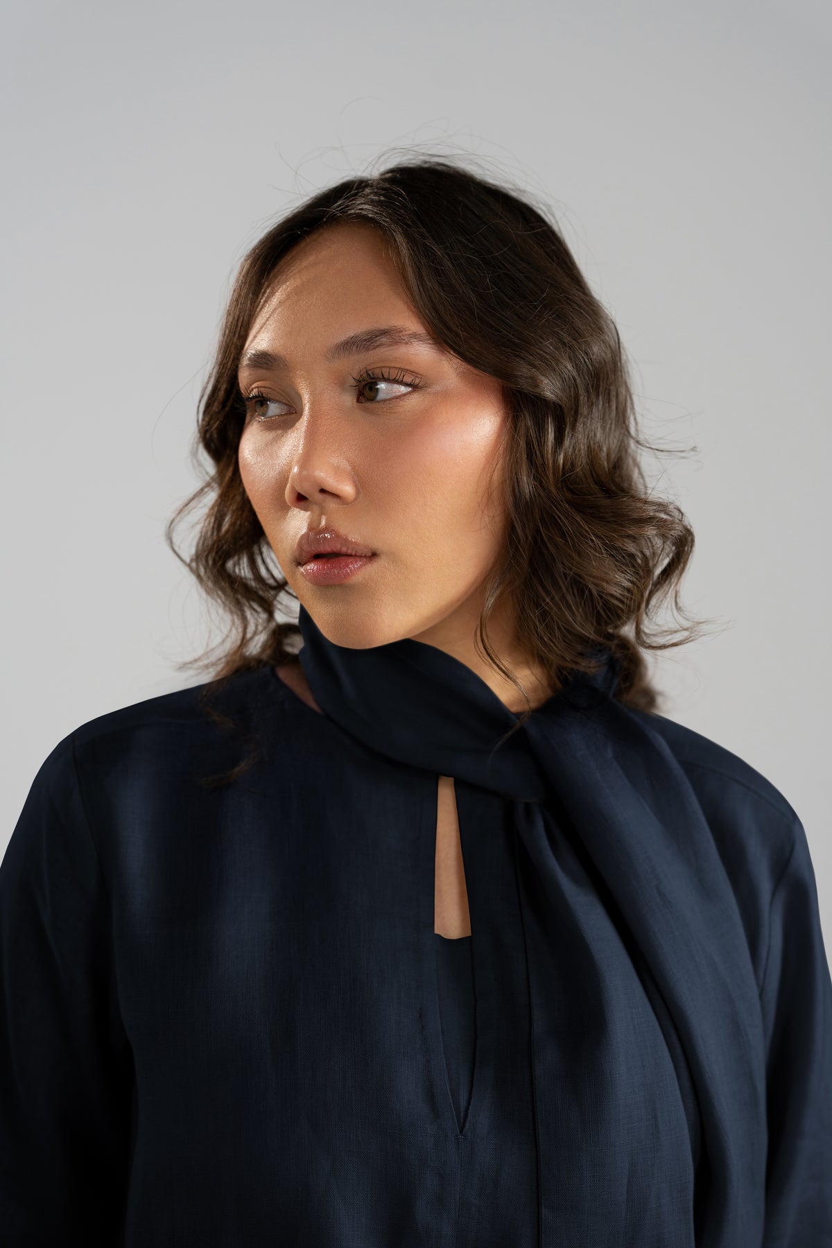 Close-up of keyhole neckline and fabric detailing on navy linen shirt