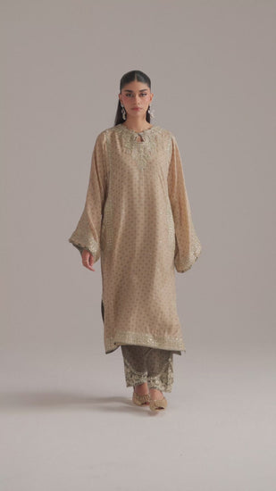 The Taupe Set by Mannam is an ivory silk phiran — a traditional long tunic silhouette — adorned with Hyderabadi tilla dori embroidery covering the front, back, sleeves and pockets. The pockets are also embroidered, and the phiran is finished with goti lace and a sequin-detailed neckline.